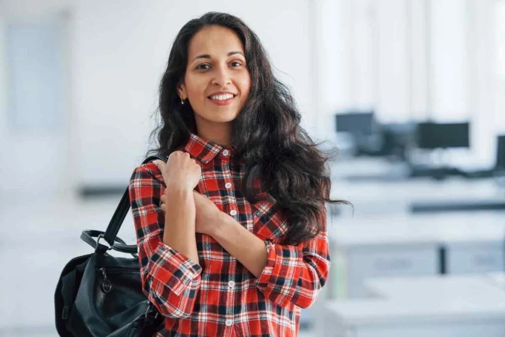 Young woman standing in an office with a bag